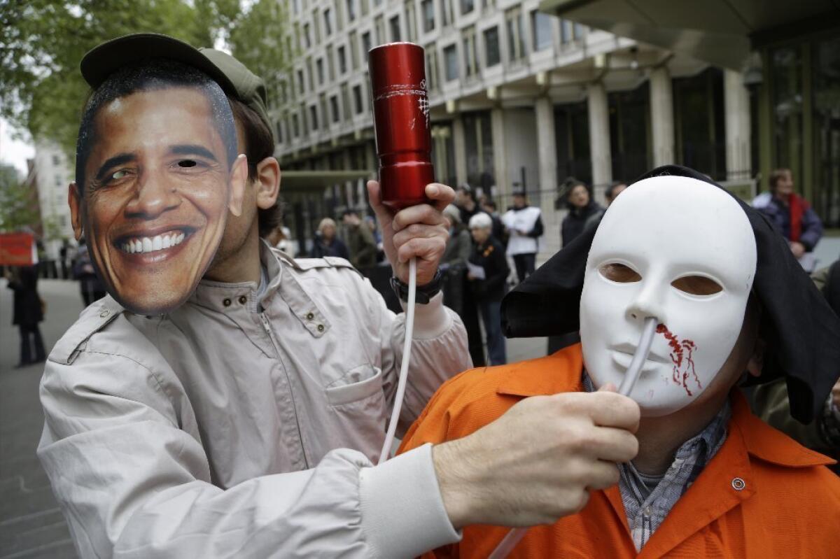 A masked protester pretends to force-feed another protester depicting a detainee of the U.S. detention facility at Guantanamo Bay during a demonstration in London last May.