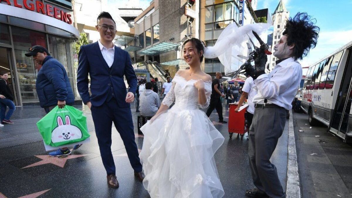 A couple from Beijing pose for wedding photos with a movie character impersonator on Hollywood Boulevard in 2018.