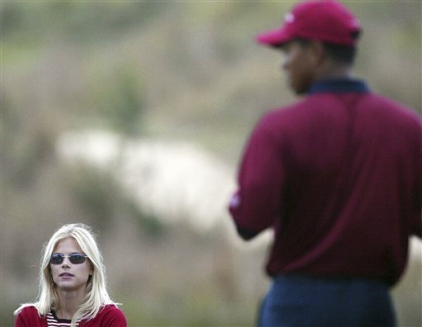 FILE - In this Nov. 23, 2003 file photo, Tiger Woods, right, stands near his then-girlfriend Elin Nordegren, left, during the final day of the Presidents Cup 2003 Golf Tournament at the Fancourt Golf Estate in George, South Africa. Amid all the headlines generated by Tiger Woods' troubles, the puzzling car accident, the suggestions of marital turmoil and multiple mistresses, little attention has been given to the race of the women linked with the world's greatest golfer. Except in the black community. (AP Photo/Themba Hadebe, File)