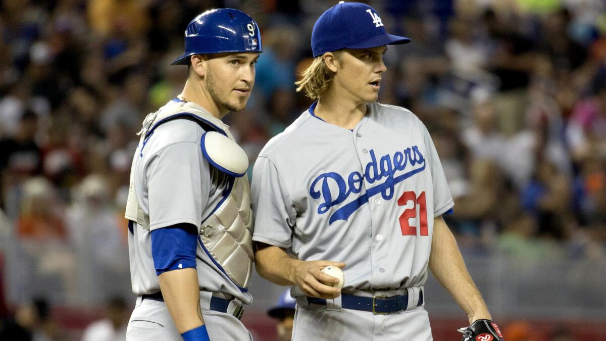 Dodgers starter Zack Greinke (21) and catcher Yasmani Grandal talk strategy during the first inning Sunday in Miami.