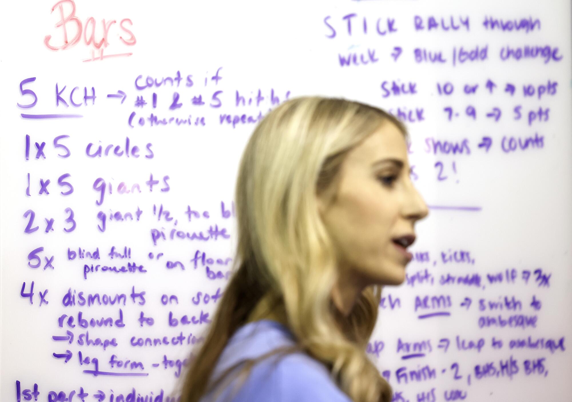 Autumn Grable stands in front a white board covered in details about the day's workout.