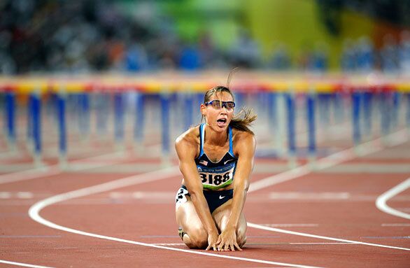 Runner Lolo Jones, on her knees, watched the replay of the 100-meter hurdles. Jones was in the lead before tripping over a hurdle.