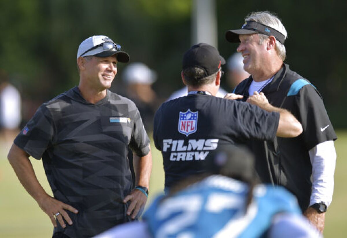 Jacksonville Jaguars general manager Trent Baalke, left, looks on as Jaguars head coach Doug Pederson is wired for a microphone during filming by NFL Films at the NFL football team's training camp, Monday, Aug. 1, 2022, in Jacksonville, Fla. (Bob Self/The Florida Times-Union via AP)