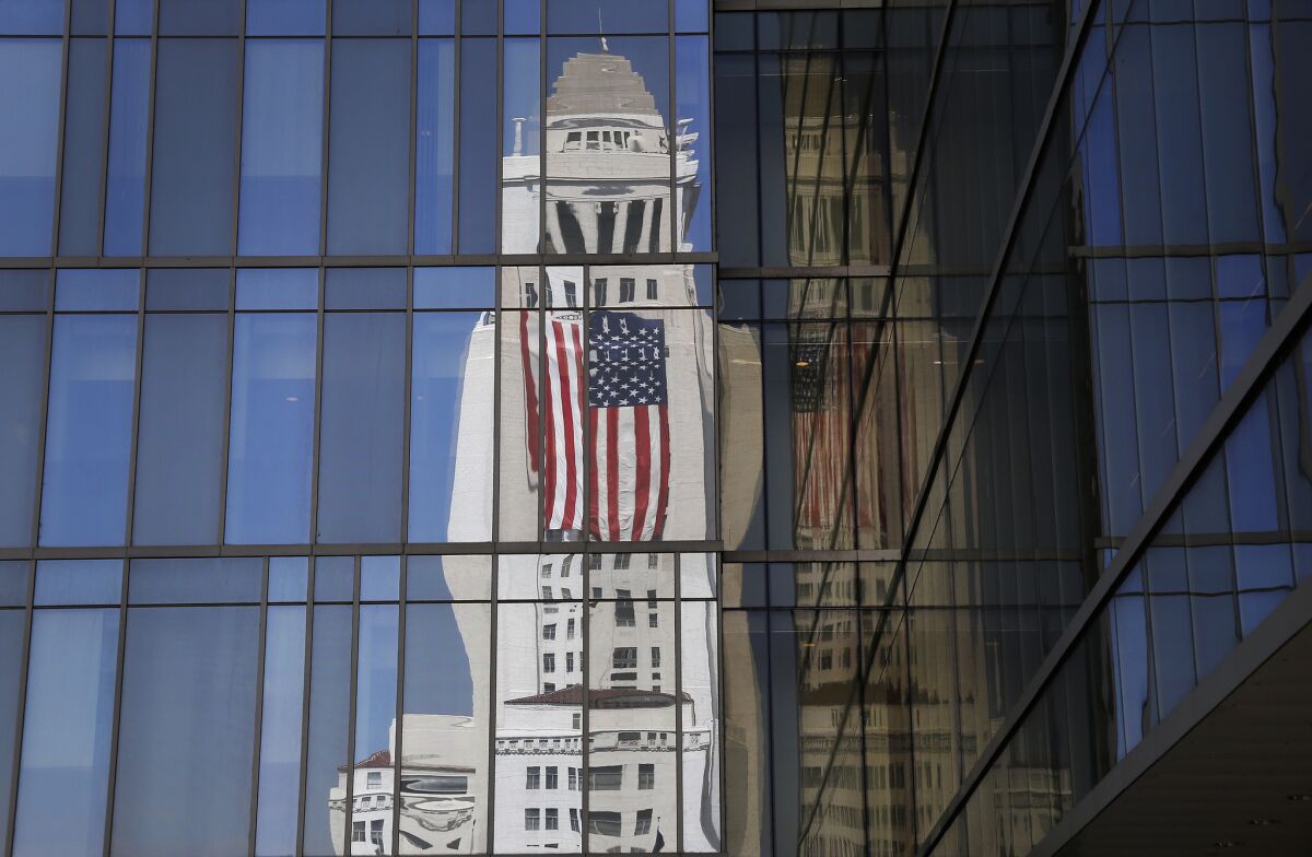 Los Angeles City Hall reflected on the windows of the LAPD Headquarters.
