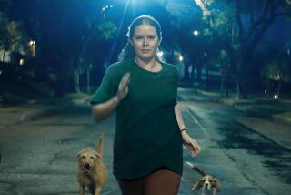 A woman runs down a street at night flanked by dogs.