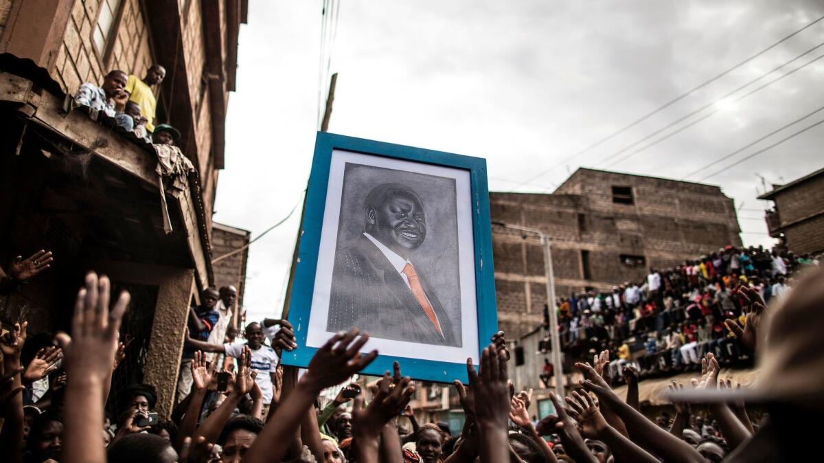 A portrait of embattled Kenyan opposition leader Raila Odinga is carried by a crowd waiting for his arrival in Mathare, a slum district of the capital, Nairobi.
