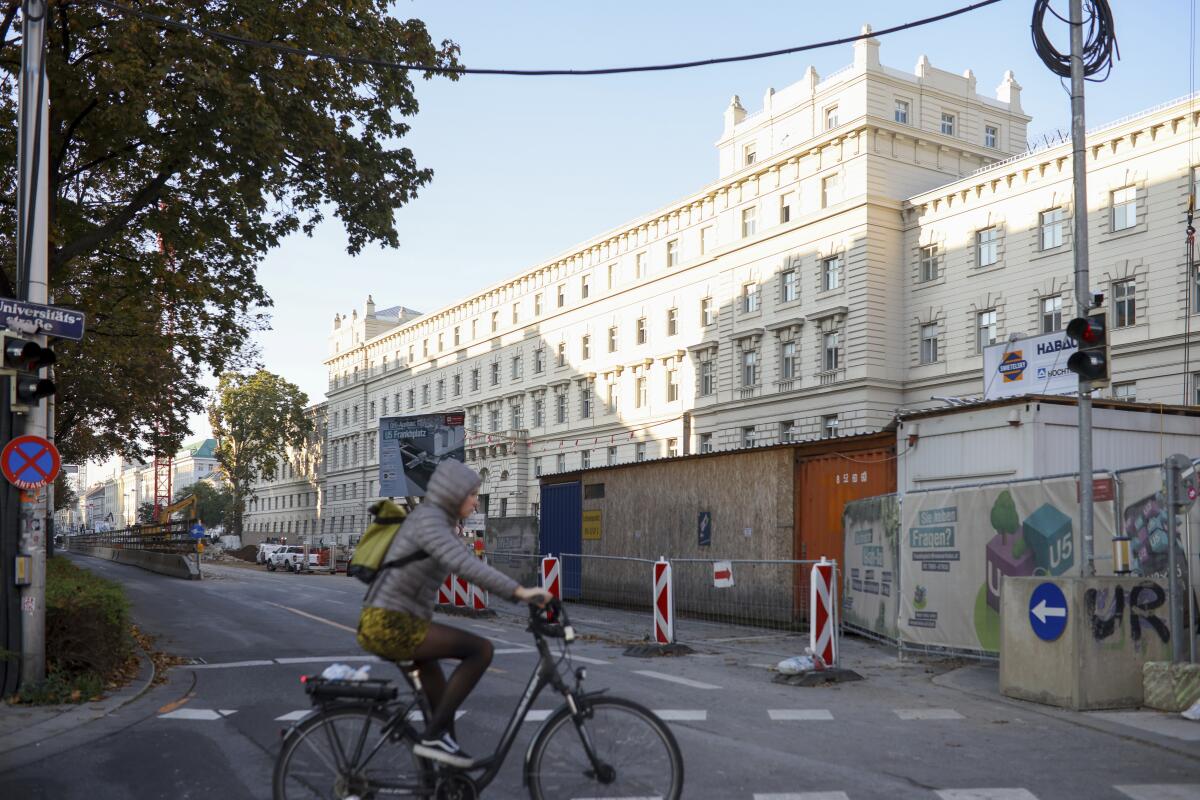 A Woman rides a bike in front of the regional court, Landgericht for Criminal Matters, in Vienna, Austria, Tuesday, Oct. 18, 2022. A trial against 6 defendants related to the terrorist attack in Vienna November 2020 starts at the court. (AP Photo/Theresa Wey)