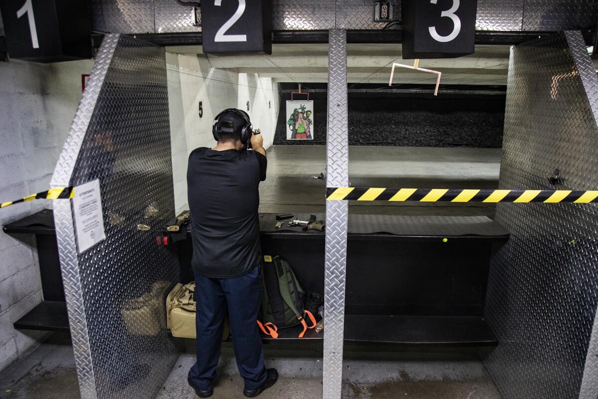 A man points a handgun downrange at a shooting range