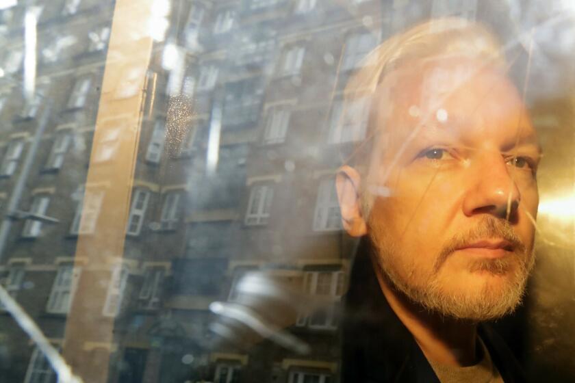 FILE - In this May 1, 2019, file photo, buildings are reflected in the window as WikiLeaks founder Julian Assange is taken from court in London. The Justice Department says a federal grand jury has returned a new indictment against WikiLeaks founder Julian Assange that does not include new charges but broadens the scope of conduct that the government believes broke the law. (AP Photo/Matt Dunham, File)