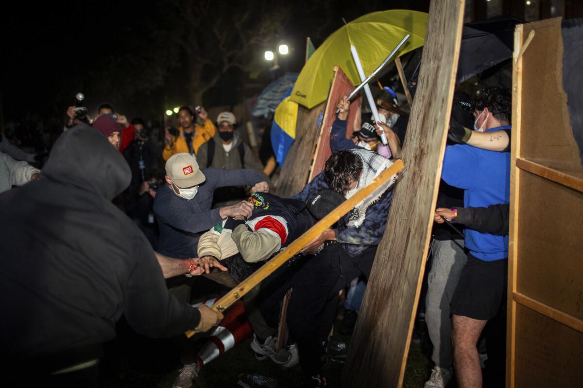 Demonstrators clash at a pro-Palestinian encampment at UCLA at night.