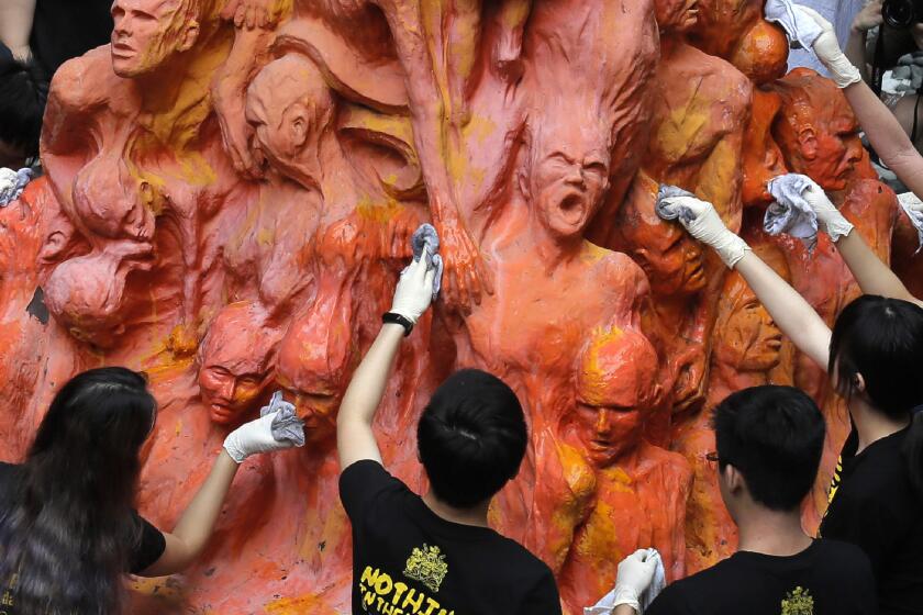 FILE - University students clean the "Pillar of Shame" statue, a memorial for those killed in the 1989 Tiananmen crackdown, at the University of Hong Kong, June 4, 2019. For Hong Kong’s pro-democracy movement, 2021 has been a year in which the city’s authorities and the central government in Beijing stamped out nearly everything it had stood for. (AP Photo/Kin Cheung, File)