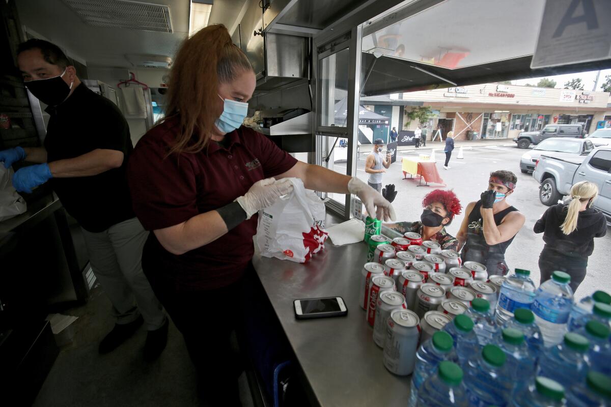 With Ramiro Rivas from operations support at left, Miguel's Jr. Homestyle Mexican Food district manager Larissa Bailey, right, adds a soda to a lunch bag during Wednesday's event.