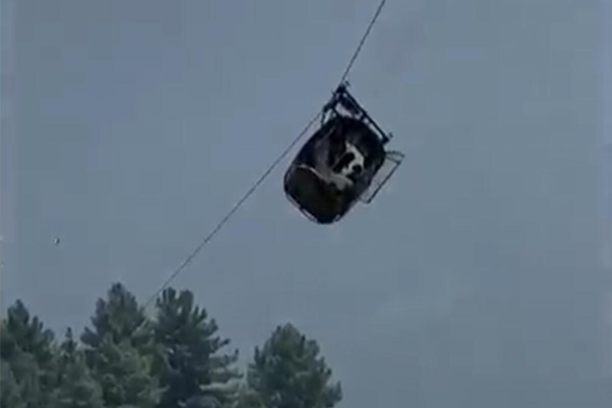 A cable car tilts as it dangles hundreds of feet above the ground.