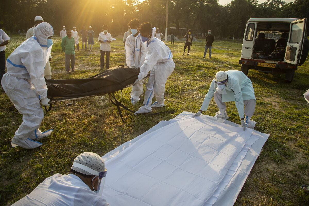 Municipal workers prepare to bury a COVID victim in Gauhati, India