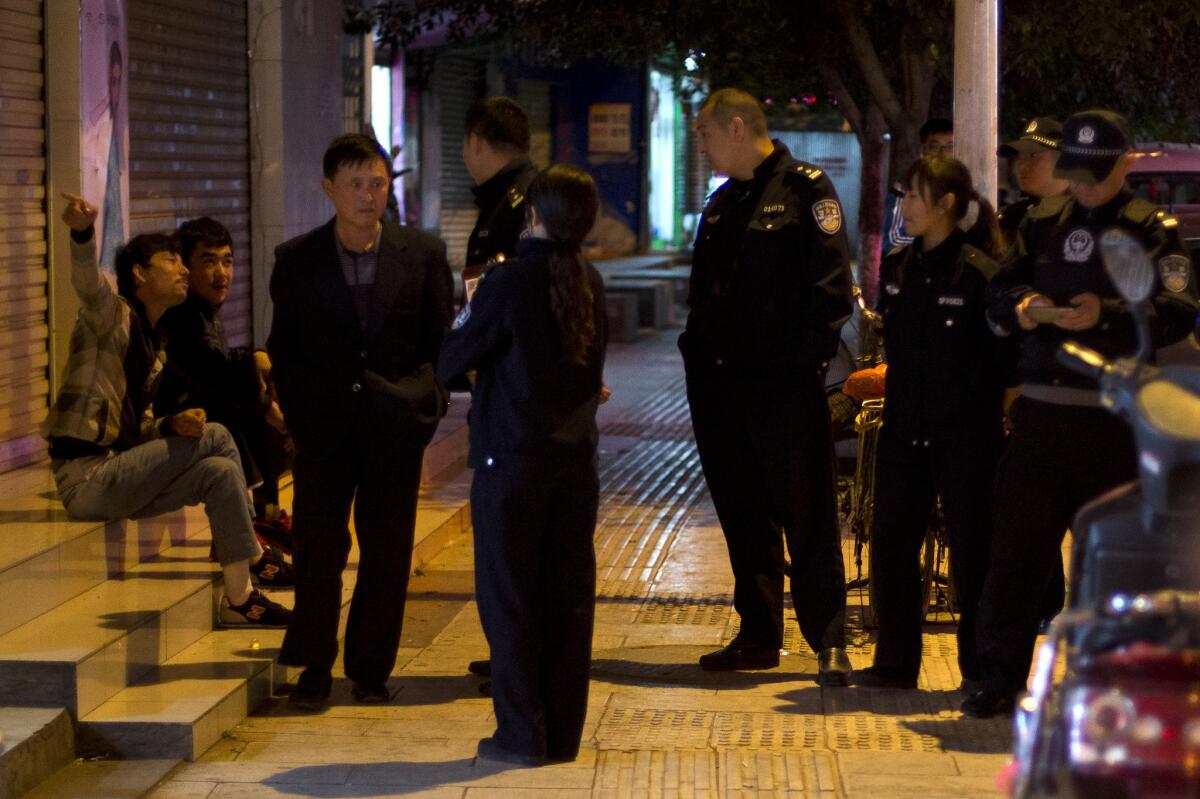 Police officers question two Uighur men, left, as a Han Chinese man walks past them Monday in Kunming, in western China's Yunnan province. Local authorities have blamed Uighur separatists for a Saturday knife attack in the city that killed 29 people.