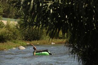 Tyrone Hart, 56, takes a ride on his lime green raft and floats down the L.A. River.