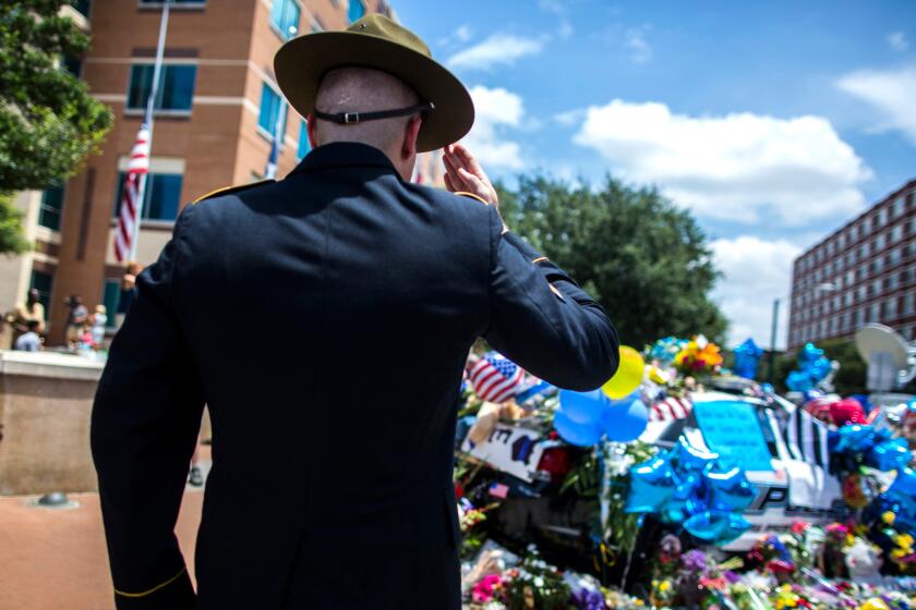 Retired Army Sgt. Chandler Davis pays his respects at a growing memorial in front of the Dallas police headquarters.