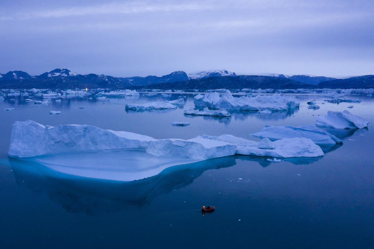 A boat navigates next to large icebergs near the town of Kulusuk in eastern Greenland.