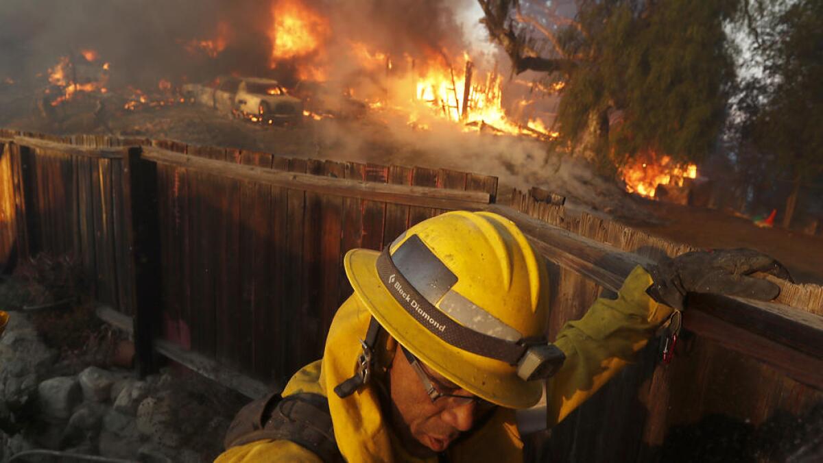 A firefighter monitors the Creek fire as it burns a house near the intersection of Johanna Avenue and McBroom Street in Shadow Hills.