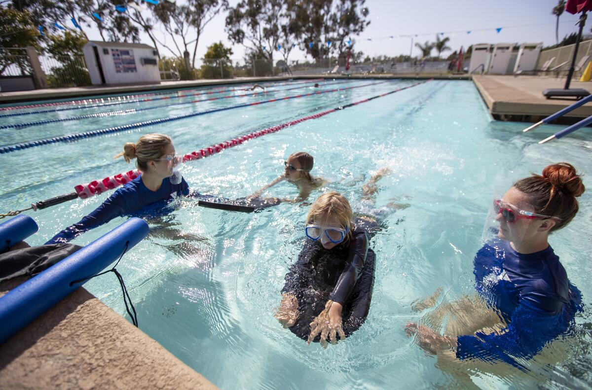 Swim instructors Ella Deshautreaux, left, and Abby Pike give swimming lessons to Scarlett and Oliver Roos.