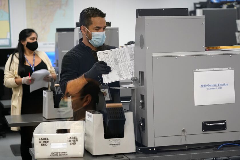 An election worker loads ballots into a scanning machine at the Miami-Dade County Board of Elections, Monday, Oct. 26, 2020, in Doral, Fla. (AP Photo/Lynne Sladky)