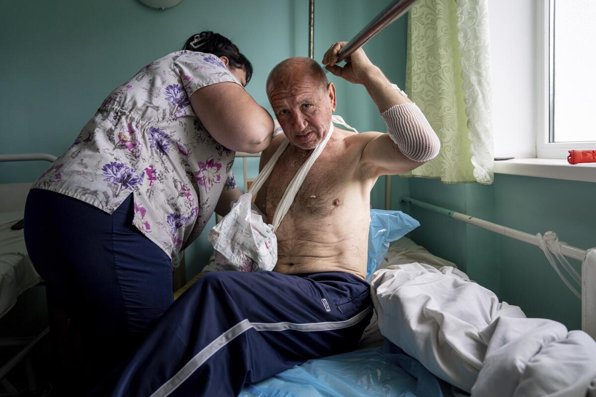 Vitalii Shpalin, 60, sits on a bed in a hospital in Kherson region, Ukraine, after he was shot while evacuating a flood zone.