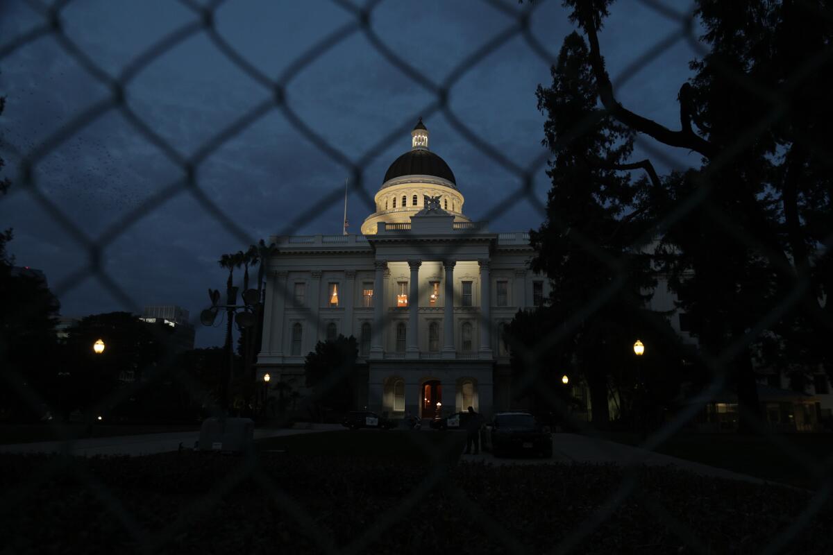 The state Capitol in Sacramento is seen through a fence.