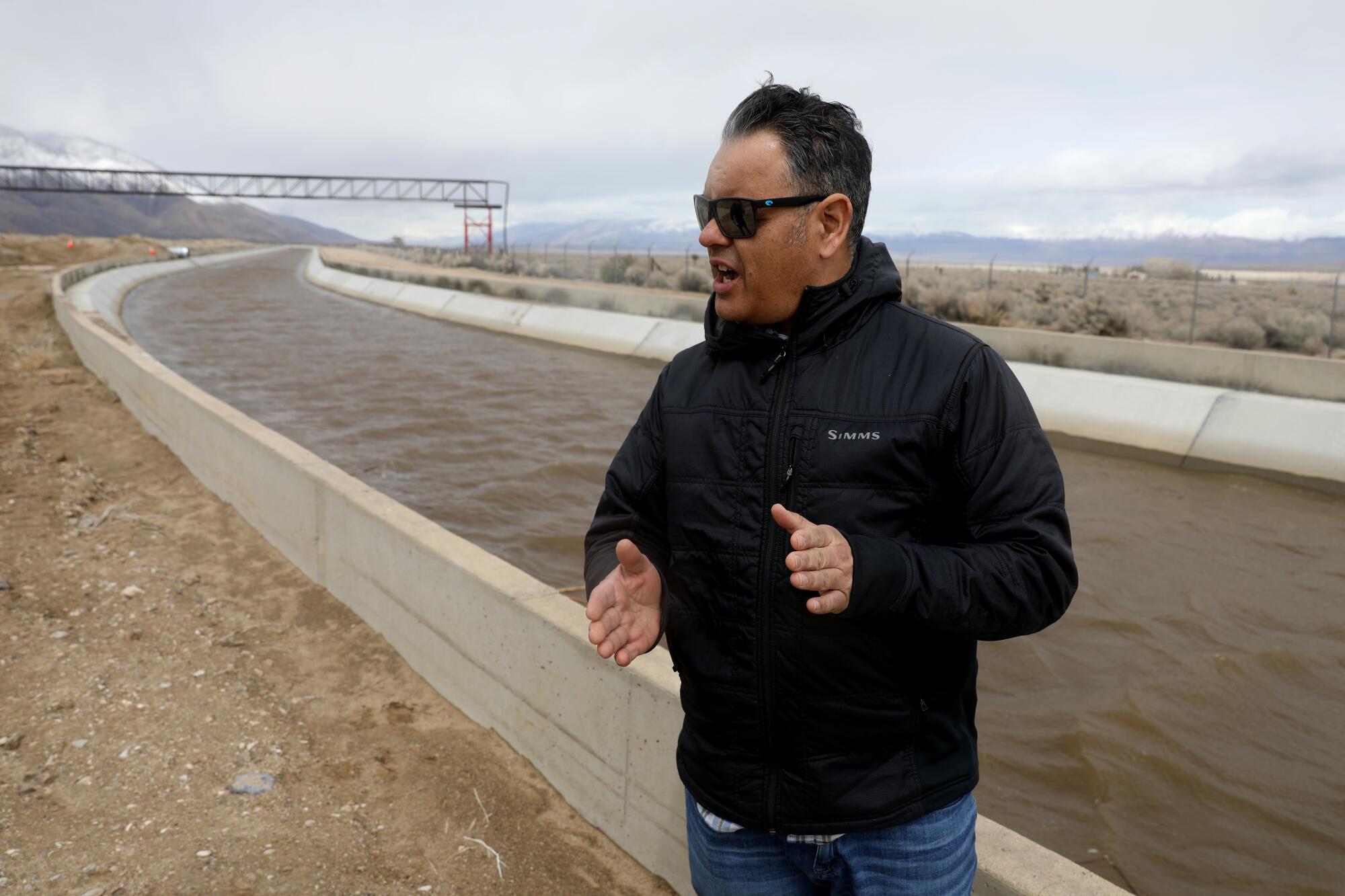 A man speaks in front of an aqueduct