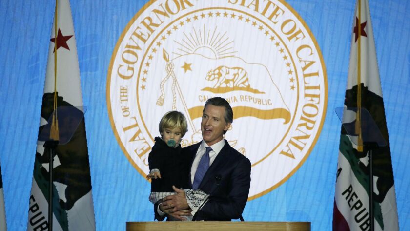 California Governor Gavin Newsom holds his son, Dutch, while speaking during his inauguration Monday in Sacrament.