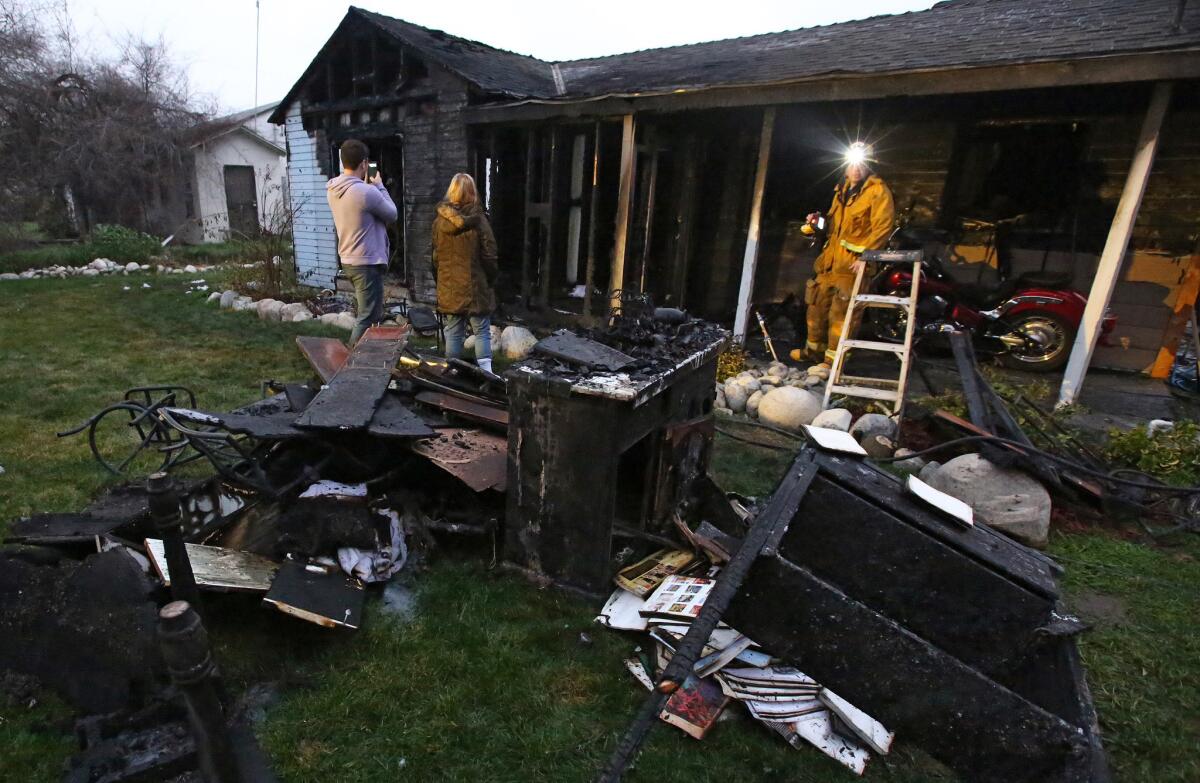 Family members look at the charred remains of their home in Azusa after a fire early Tuesday morning.