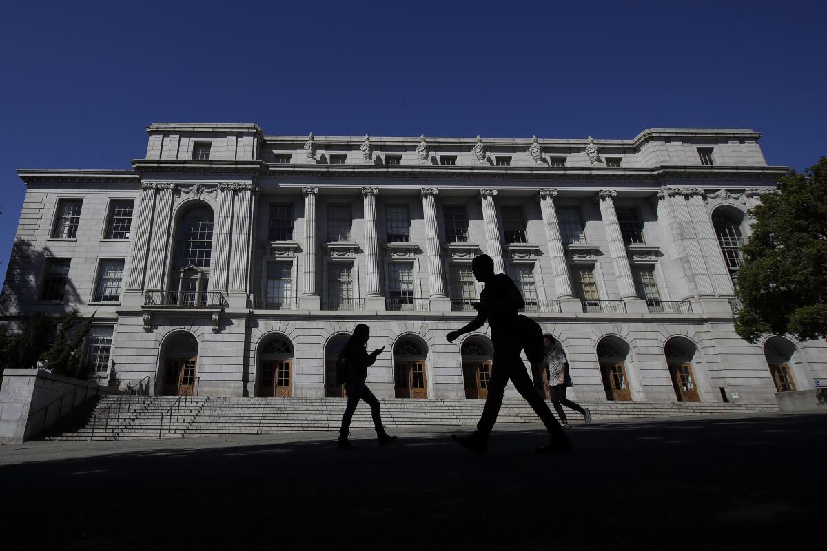 People walk in front of an official-looking building.