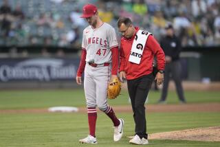 Los Angeles Angels pitcher Griffin Canning (47) walks off the field with a trainer after being taken out.