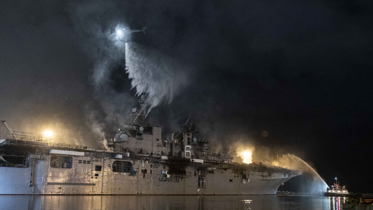 A helicopter combats a fire aboard the amphibious assault ship Bonhomme Richard