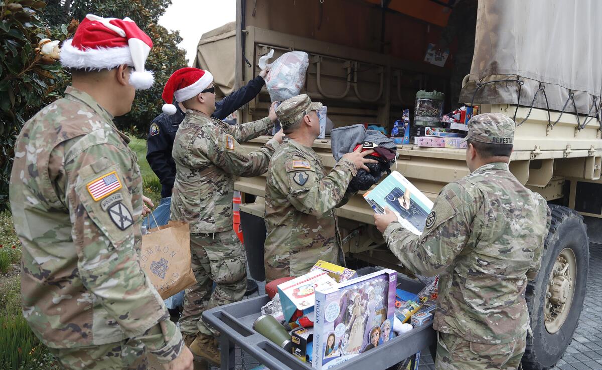 Members of local branches of the military load a truck with hundreds of toys.