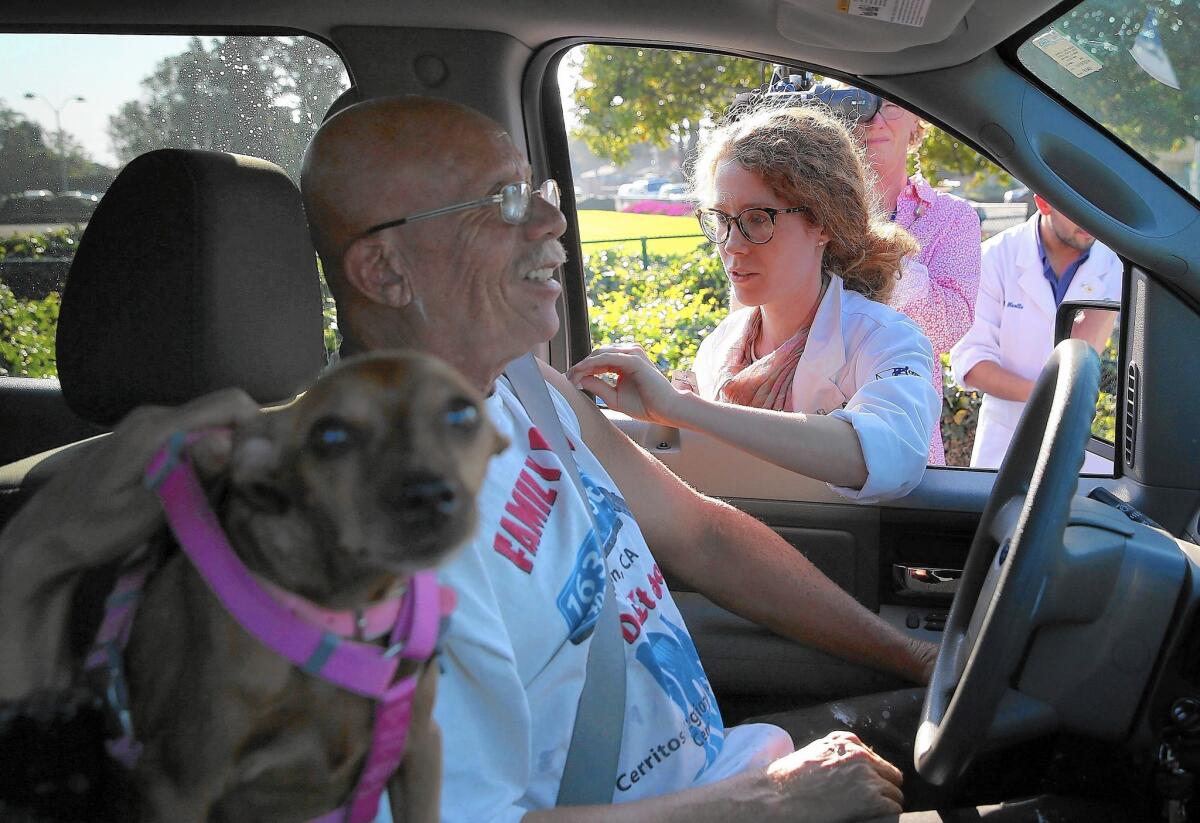 Medical student Caitlin Harris administers a flu vaccine to a person in a car during a drive-through flu shot clinic at Doctors Medical Center in San Pablo, Calif.