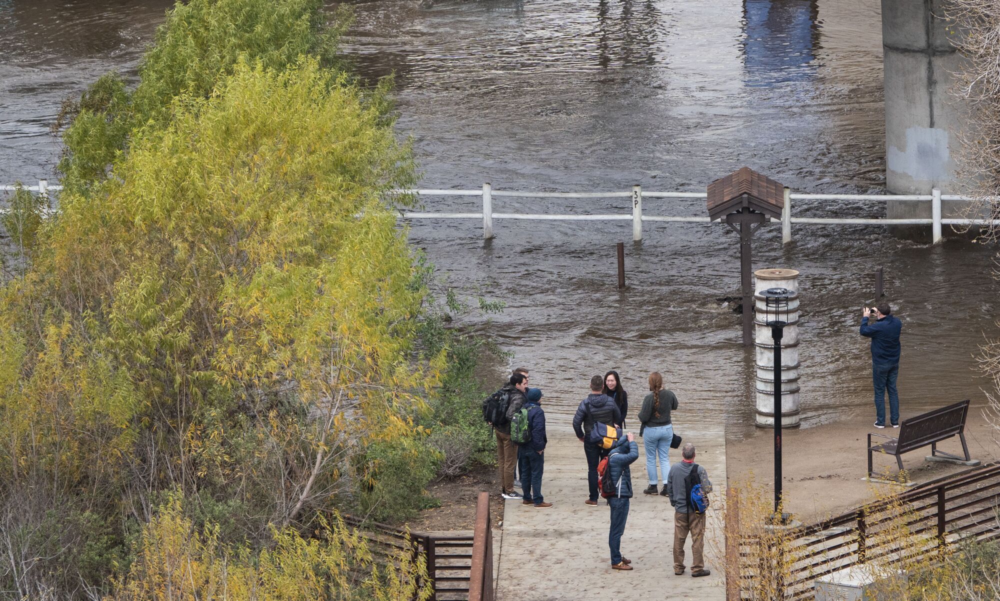 People check out the swollen San Diego River near the Town and Country Resort in Mission Valley.