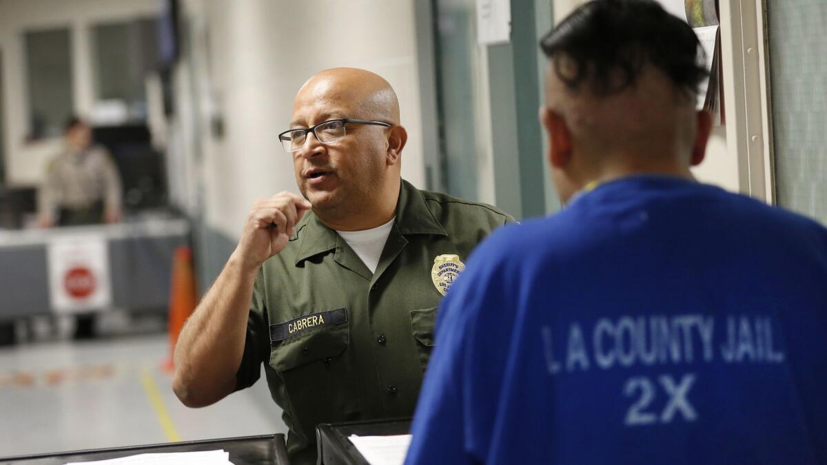 Los Angeles County Sheriff’s custody assistant Rodolfo Cabrera serves an inmate with a detainer form from the U.S. Department of Homeland Security and processes him for possible transfer to federal immigration custody on May 13.