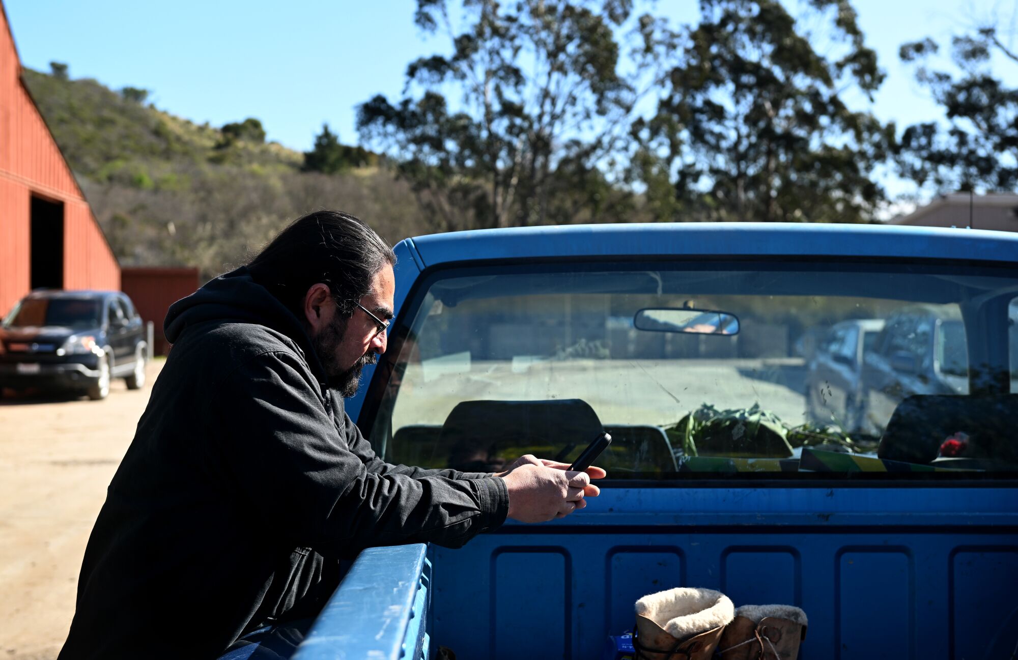 A man leans over the side of a blue pickup truck bed.