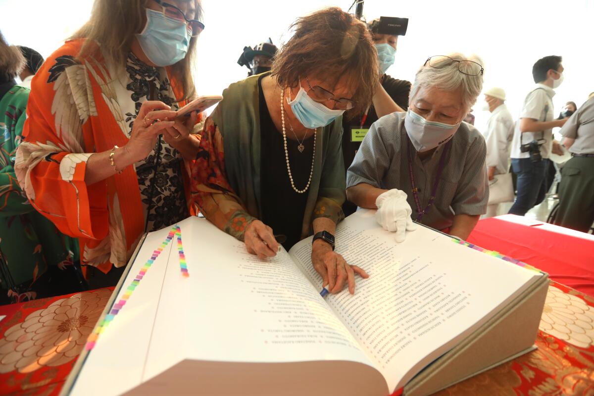 Three people looking at a large book