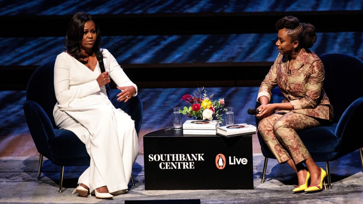 Former First Lady Michelle Obama, left, speaks with Nigerian author Chimamanda Ngozi Adichie at the Royal Festival Hall in London on Dec. 03.