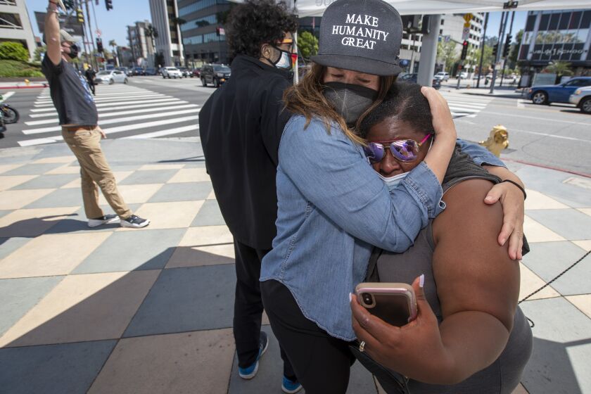 SHERMAN OAKS, CA - APRIL 20: Supporter Katie Mau, left, embraces Latora Green, right, as the verdicts are read in the Chauvin trial on Tuesday, April 20, 2021 in Sherman Oaks, CA. Green has been standing in front of the Sherman Oaks Galleria on Ventura Blvd. and Sepulveda for 325 straight days. (Brian van der Brug / Los Angeles Times)