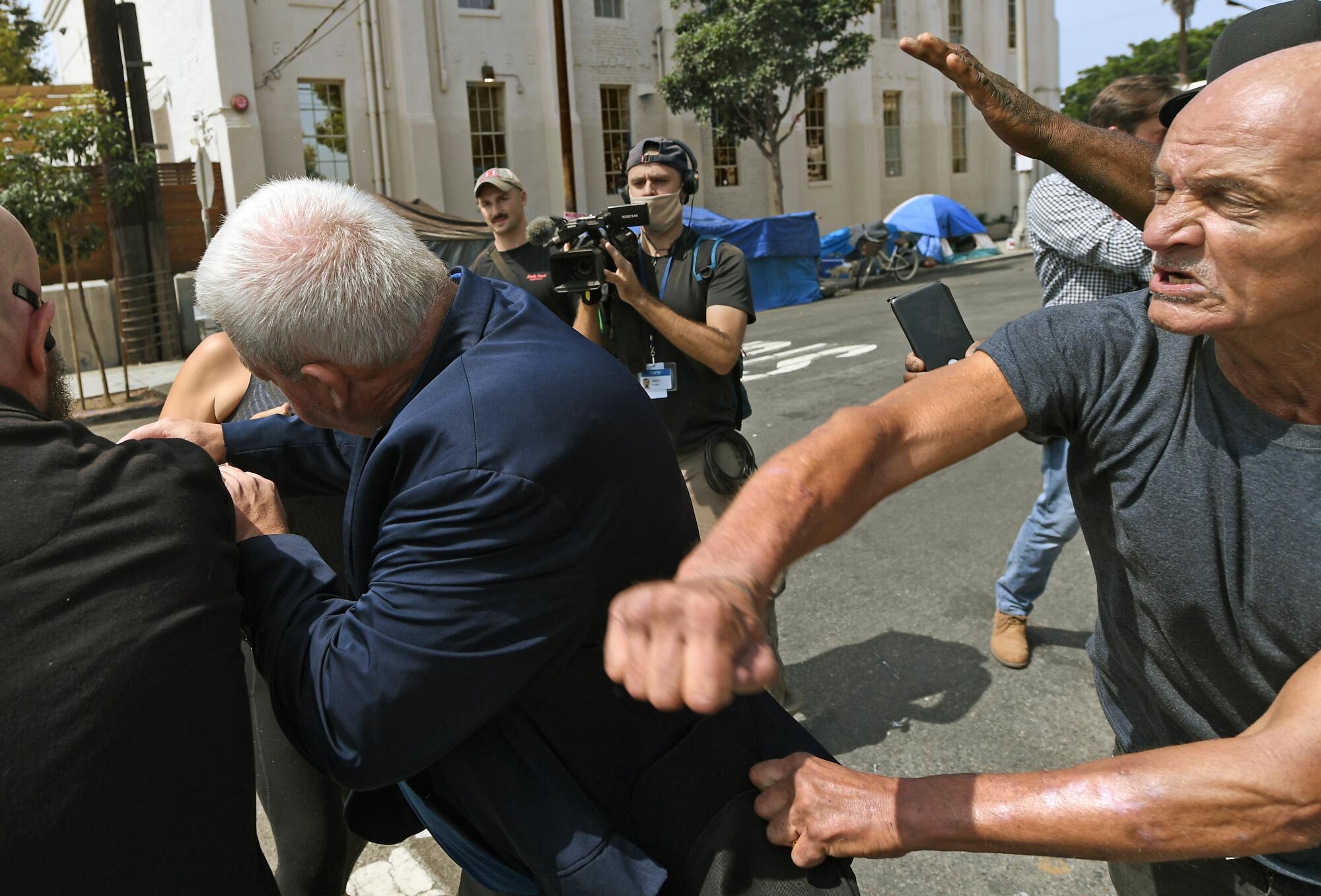 A man, right, swings his arm at a man in a suit