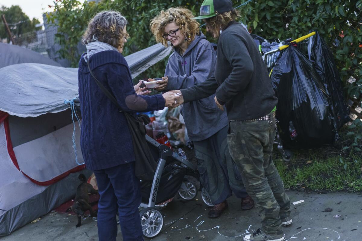 Cal Peternell's wife Kathleen Henderson helps him hand out bowls of Indian dal to the homeless in Berkeley, Calif.