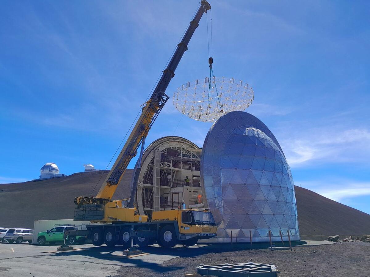 A crane removes equipment from an observatory on a mountain summit. 