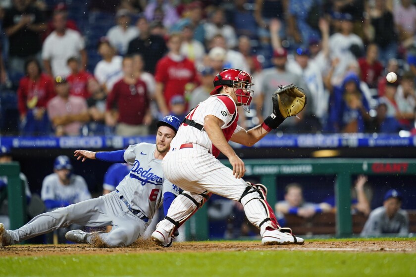Dodgers' Trea Turner, left, slides past Phillies catcher J.T. Realmuto during the sixth inning Tuesday in Philadelphia.