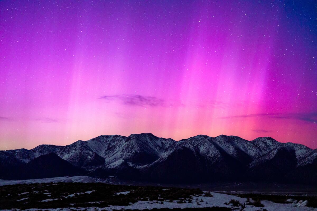 The northern lights are seen over mountains.
