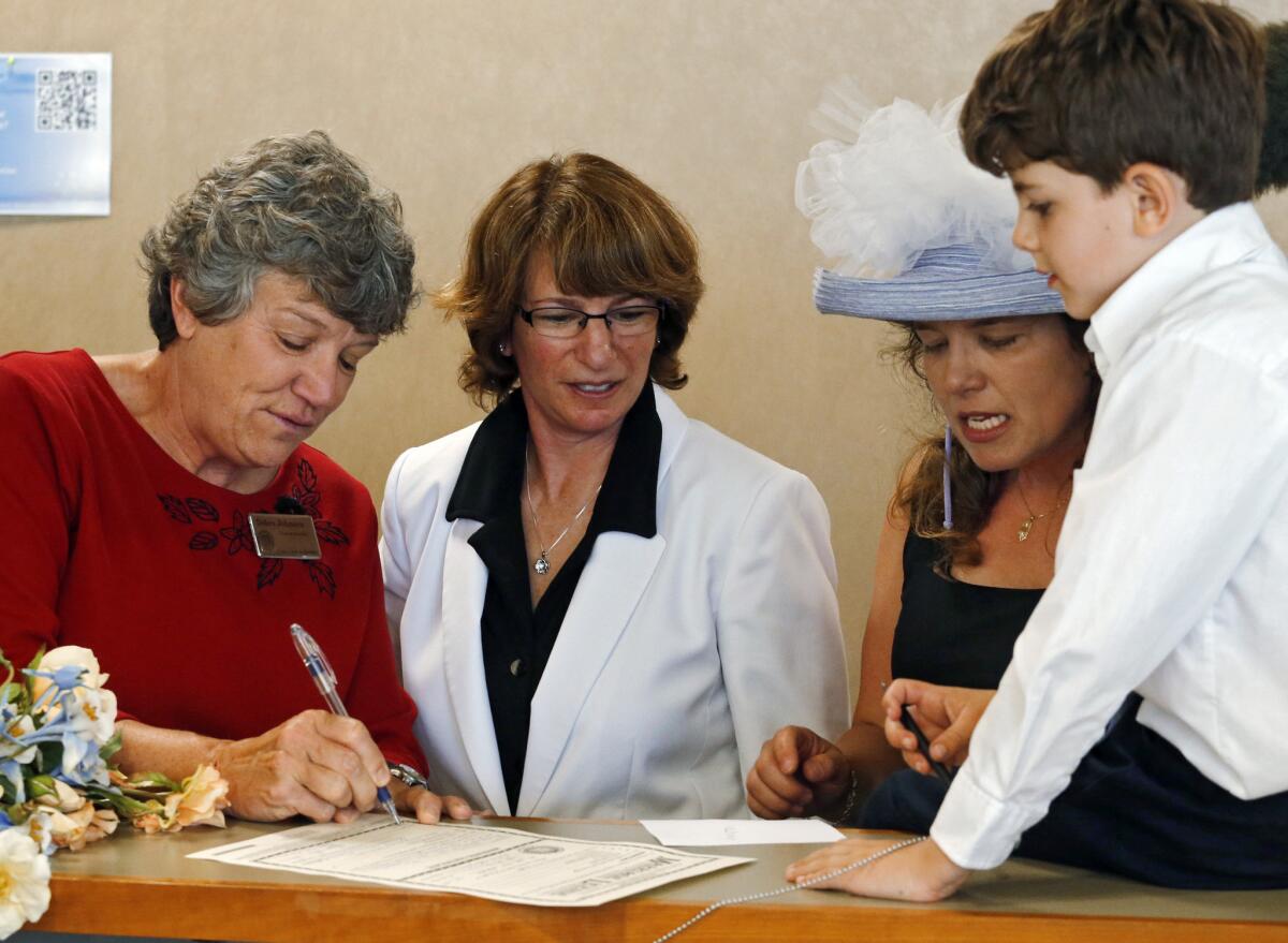 Denver County Clerk Debra Johnson, left, signs the marriage license of Fran Simon and Anna Simon as their son Jeremy watches at the Denver County clerk's office Thursday. On Friday, the Colorado Supreme Court ordered Denver to stop issuing licenses to same-sex couples.