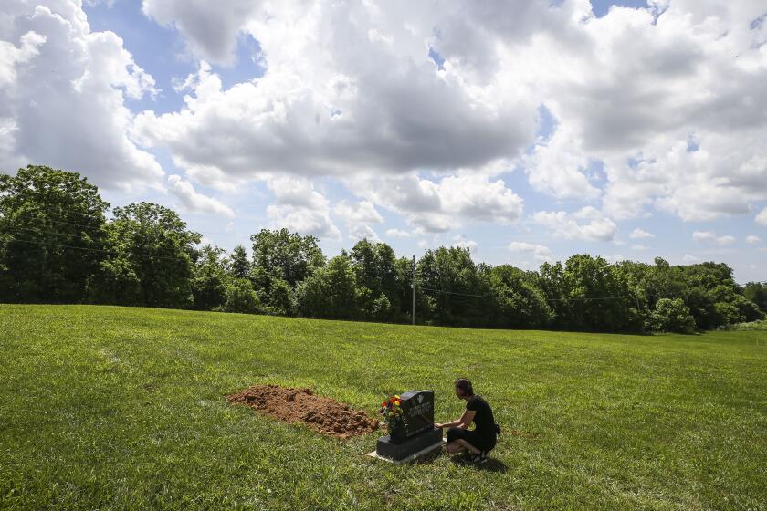 FILE - Kelly Vervillas, of Shepherdsville, Ky. visits the gravesite of the unknown boy who was found in a suitcase in April 2022 in Washington County on June 1, 2022, in Salem, Ind. A boy found dead inside a suitcase last spring in rural southern Indiana has been identified as a 5-year-old from Georgia, and police said Wednesday, Oct. 26, that the child's mother and another woman are suspects in his death. (Matt Stone/Courier Journal via AP, File)