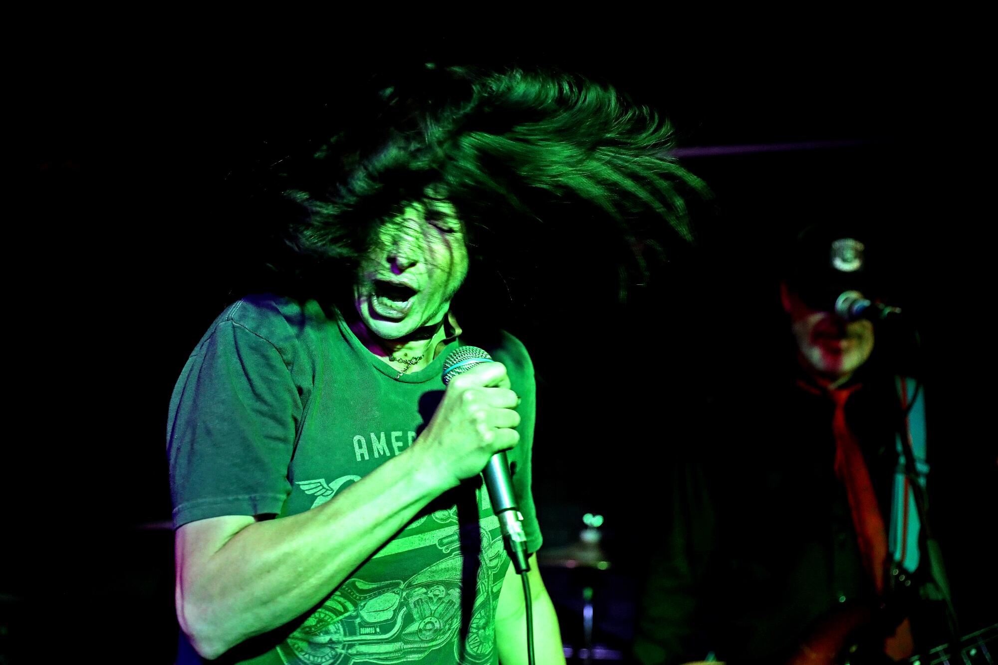 A person sings on stage, with hair flying
