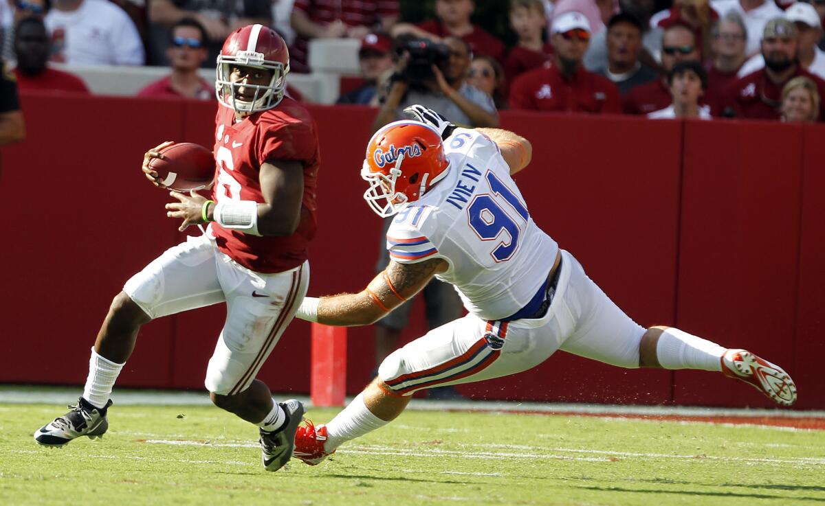 Alabama quarterback Blake Sims, left, scrambles around Florida defensive lineman Joey Ivie on Saturday in Tuscaloosa, Ala.